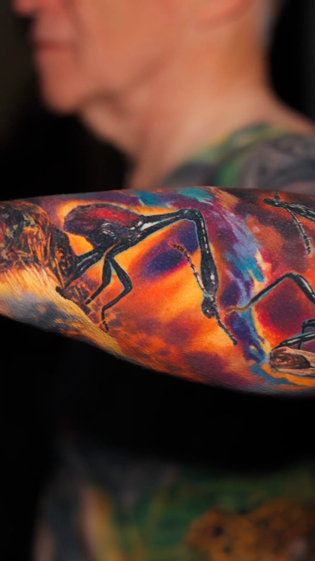 Großer Giraffenhalskäfer und Hintergrund von der Seite, im Hintergrund unscharfe Silhouette des Kunden – Tattoo auf dem Unterarm