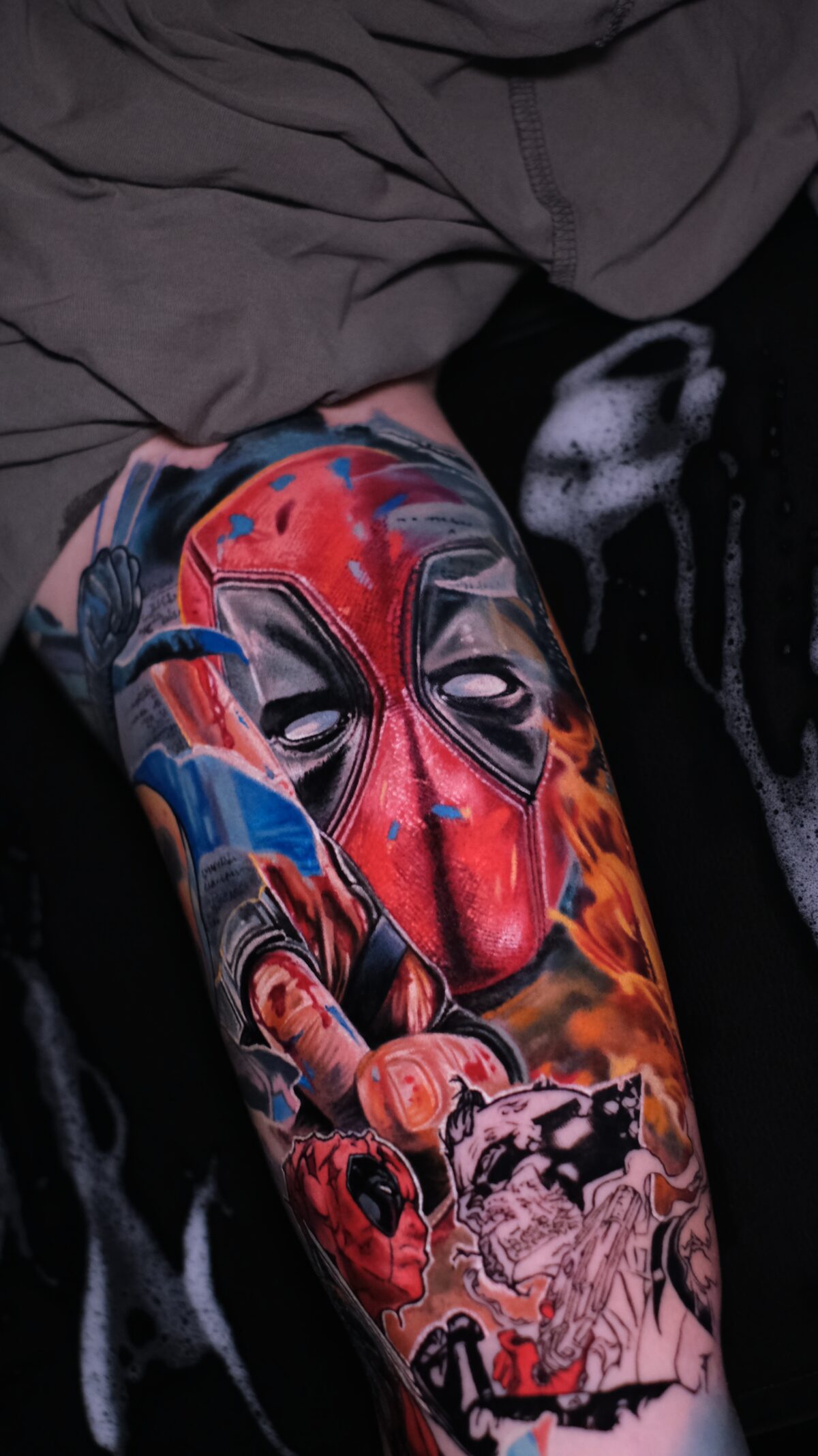 Kompletter Deadpool-Sleeve auf dem Arm: Maske, Mittelfinger und Comic-Deadpool in Color-Realism, Tätowierer Wrocław.
