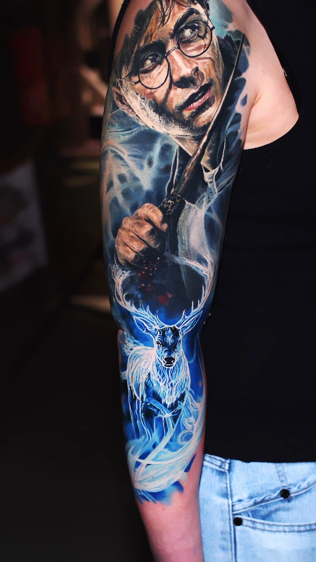Kompozycja na przedramieniu: świetlisty jeleń i iskry – tatuaż patronus, realizm w kolorze
