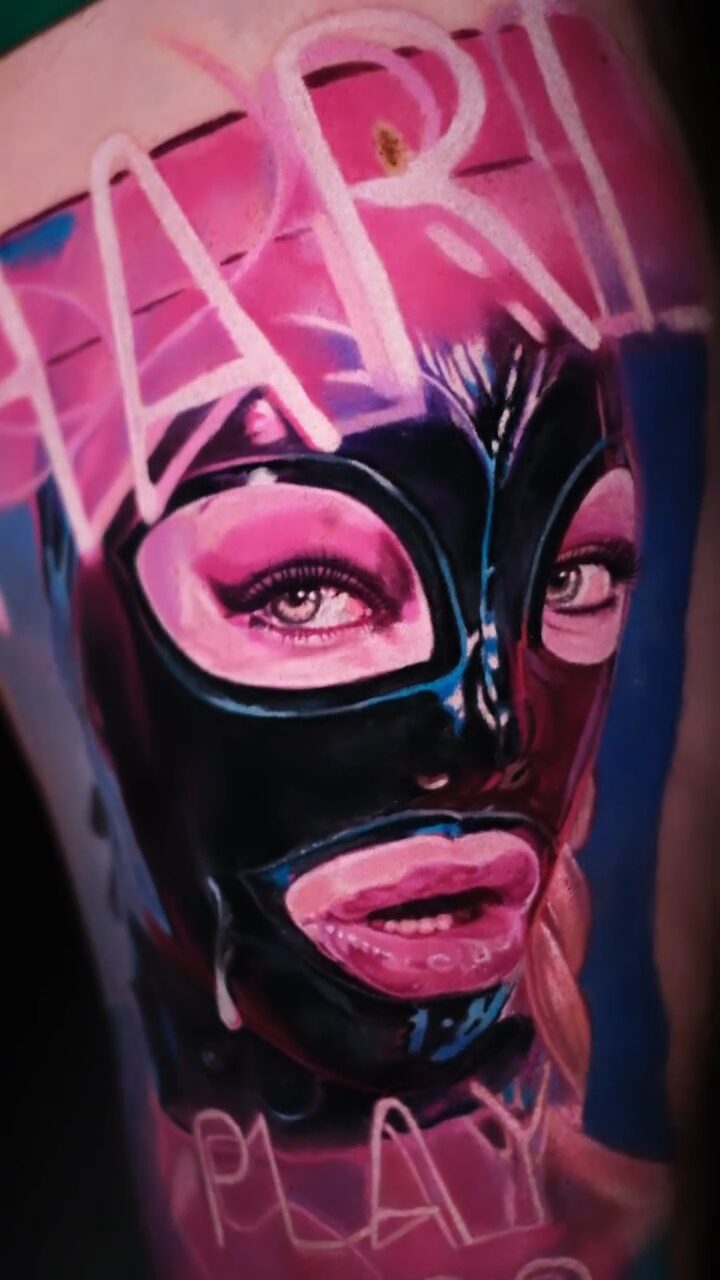 Hyperrealistisches Tattoo einer Frau in Latexmaske am Oberschenkel – Neon-Schriftzug PLAY HARD