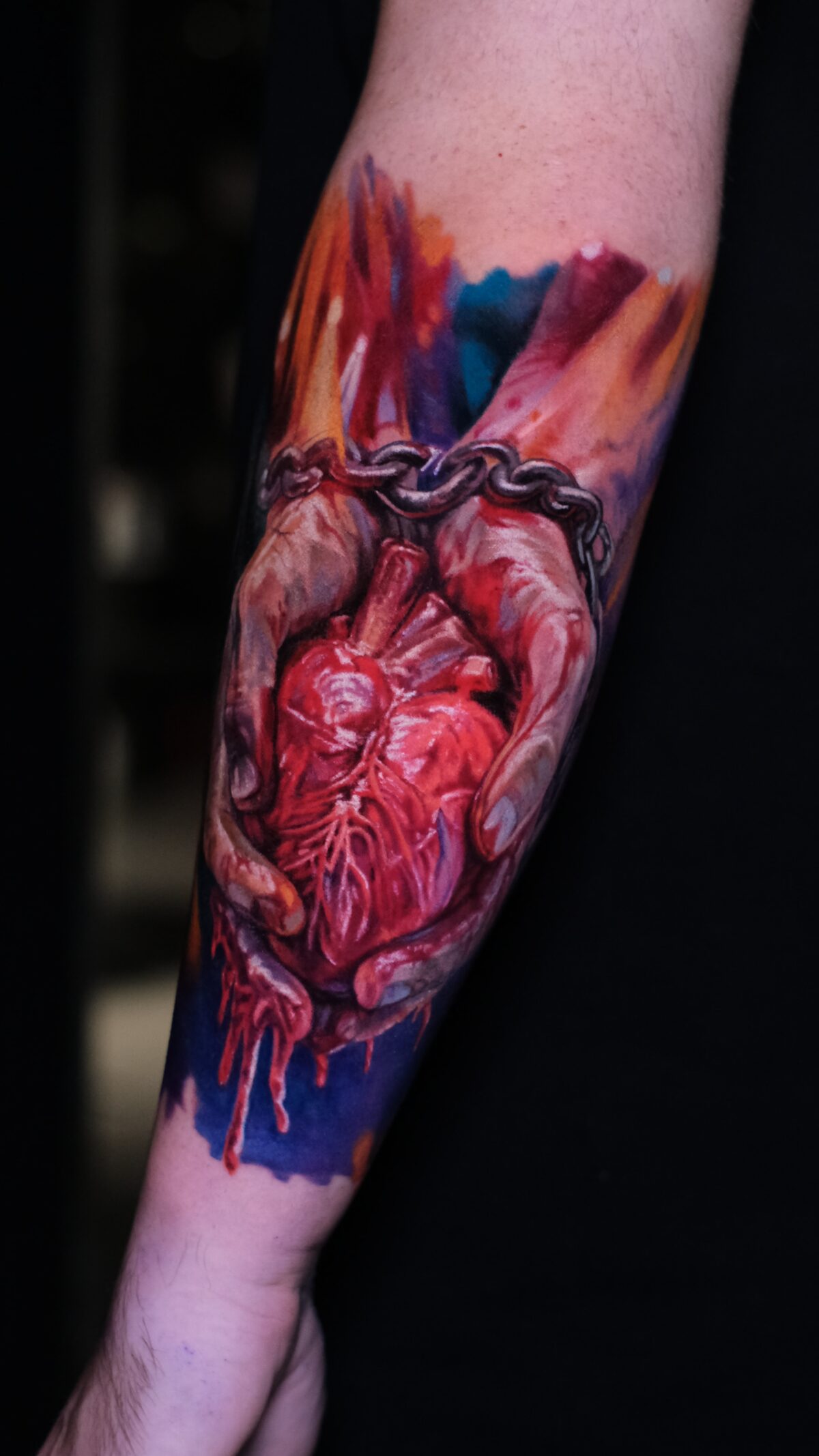 Pełny widok tatuażu na przedramieniu – serce anatomiczne w dłoniach, łańcuch, watercolor, Wrocław