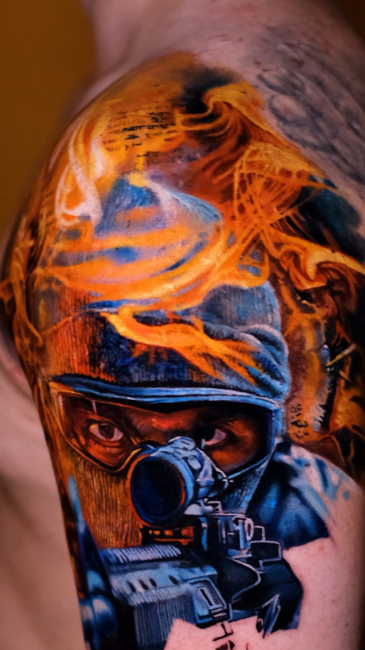 Hauptbild: gesamtes Soldaten-Tattoo im Feuer auf der Schulter, starker Kontrast zwischen Türkis und Orange, Tätowierer Wrocław.
